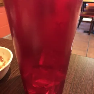 a red glass with a bowl of food in the background