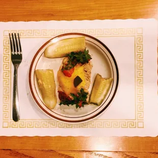 A tuna melt with American cheese, garnished with strawberry tops and pickles.