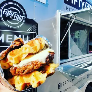 a person holding a sandwich in front of a food truck