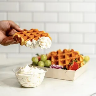 a waffle being dipped with whipped cream
