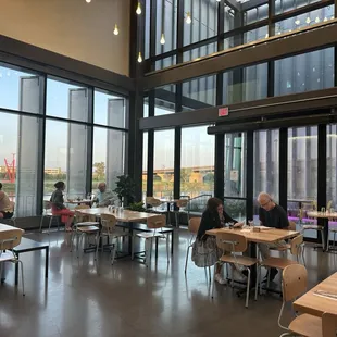 people sitting at tables in a restaurant with large windows