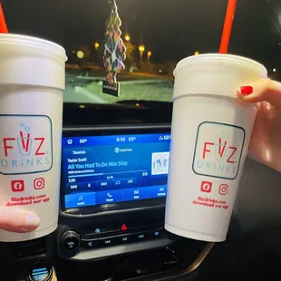 a hand holding two cups of fiiz drink