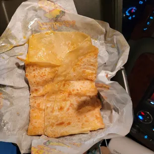 a person holding a piece of cheesy bread