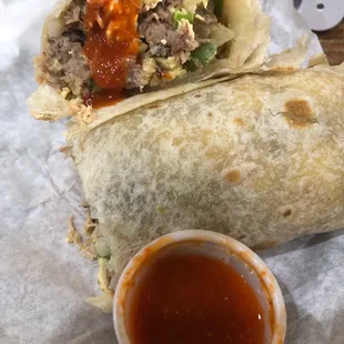 a burrito with a side of sauce