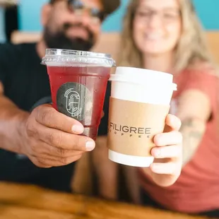  man and a woman holding two cups of coffee