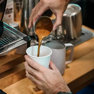  person pouring coffee into a cup