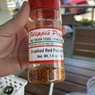 a hand holding a jar of crushed red pepper