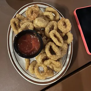 a plate of fried onion rings with ketchup and ketchup