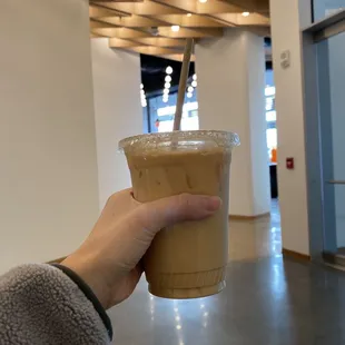 a hand holding a cup of iced coffee