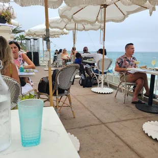 a group of people sitting at tables with umbrellas