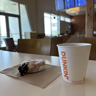 Good ole' cup of DD coffee and donut with flight arrival times in the background