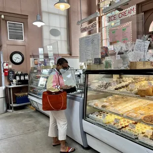 a woman standing in front of a display of pastries