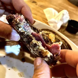 a hand holding a half eaten sandwich