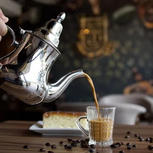 a person pouring coffee into a glass
