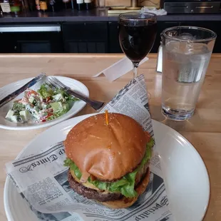 a burger and a glass of wine on a table