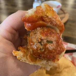 a hand holding a piece of meatball