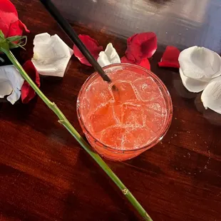 glass of cocktail with a straw and rose petals