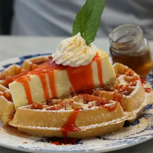 a plate of waffles topped with whipped cream and syrup