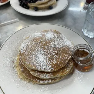 a stack of pancakes with powdered sugar and blueberries