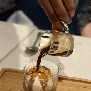 a person pouring coffee into a glass