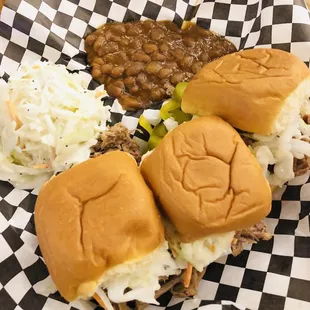 a pulled pork sandwich with beans and coleslaw