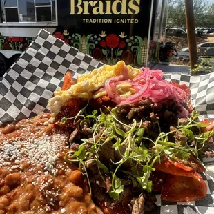 Carne Asada Chilaquiles with beef chorizo beans &amp; scrambled eggs. Topped with citrus pickled onions, Cotija cheese, &amp; micro cilantro.