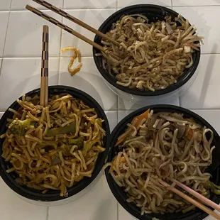 three bowls of noodles and chopsticks