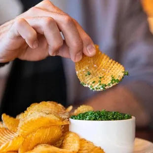 a person dipping a snack into a bowl of chips