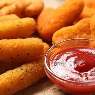 a bowl of ketchup next to a pile of fried tater tots