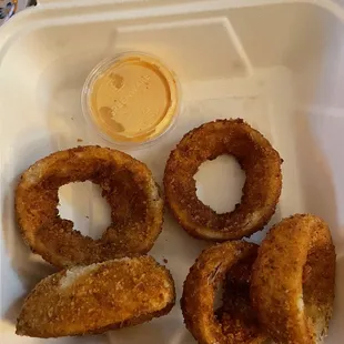 four fried donuts in a styrofoam container