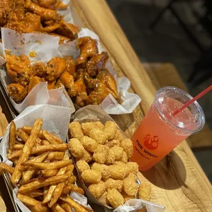 a tray of chicken wings, fries, and a drink