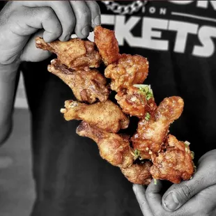a person holding a piece of fried chicken
