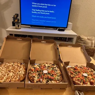 four pizzas sitting in front of a flat screen tv