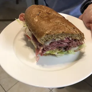 a person holding a plate with a sandwich on it