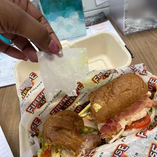 a person taking a bite out of a sub