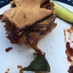 a half eaten sandwich and a pickle