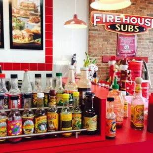 a red counter with bottles of hot sauce and condiments