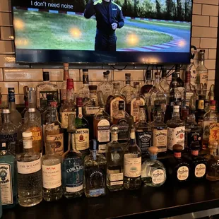 a man standing in front of a bar full of liquor bottles