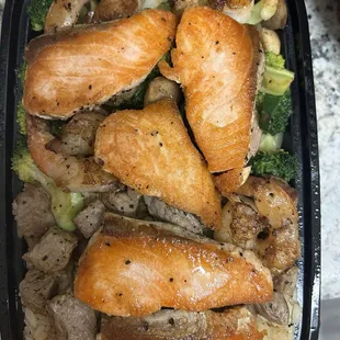 Hibachi Salmon with shrimp and steak on top of fried rice with veggies.