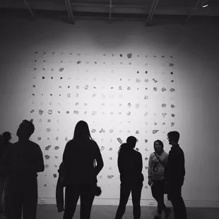 a group of people standing in front of a wall with drawings on it