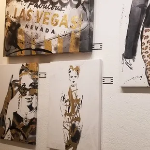 a wall of paintings and a phone charger