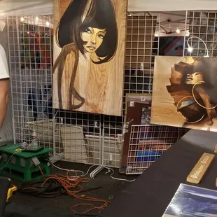 a man standing in front of a table with art on it