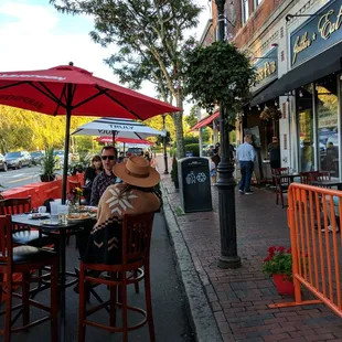 people sitting at a table under umbrellas