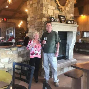 a man and woman standing in front of a fireplace