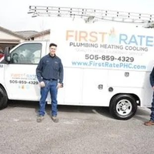 A picture of two technicians standing in front of a First Rate Plumbing, Heating &amp; Cooling work truck in front of a customer'...