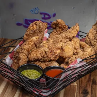 a basket of fried chicken with dipping sauce
