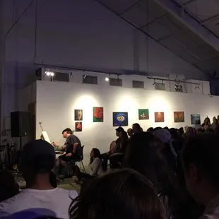 a group of people sitting in a room with paintings on the wall