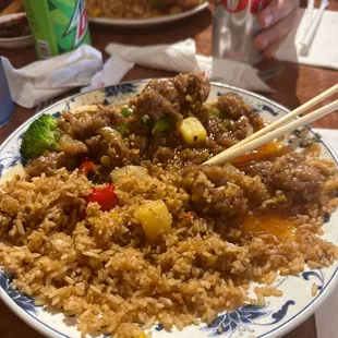 a plate of rice and meat with chopsticks