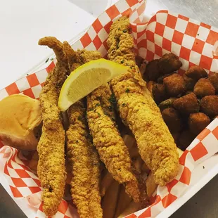 Catfish dinner with side fries,  fried okra and a sweet dinner roll