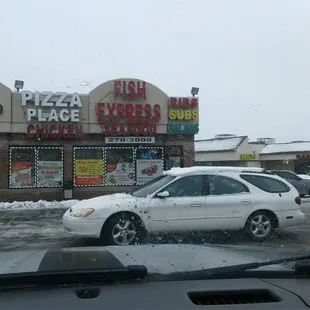 a white car in front of a pizza place